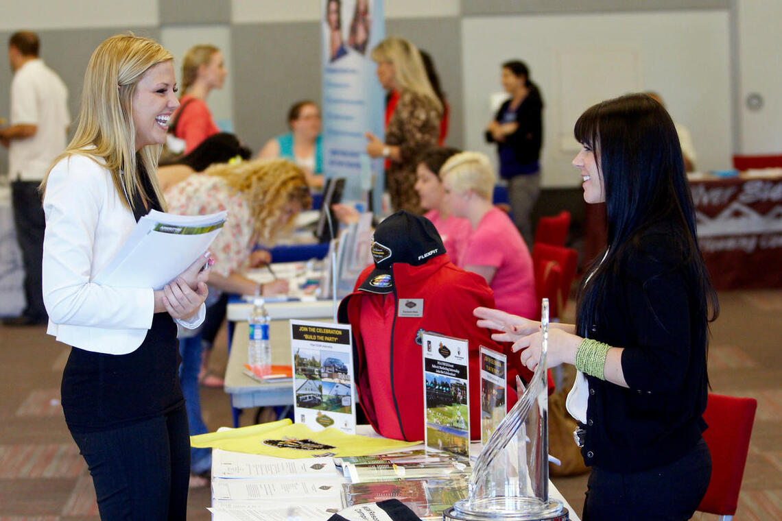 A woman talking to another woman at a booth.