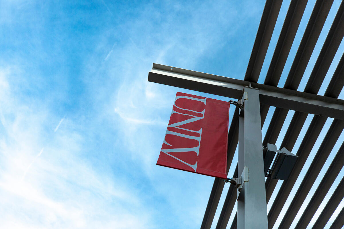 A UNLV banner hangs against the background of a bright blue sky