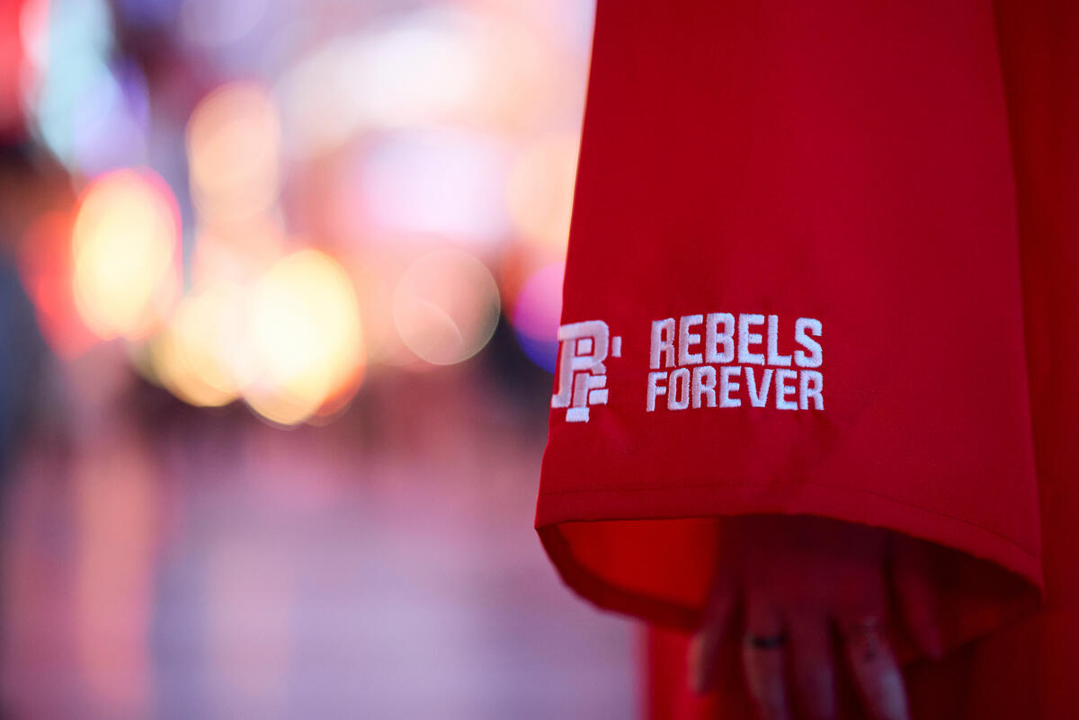 A closeup on the sleeve of a red UNLV graduation gown bearing the words &quot;Rebels Forever&quot;