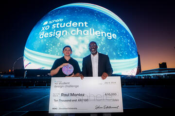older man and male student holding large check for $10,000