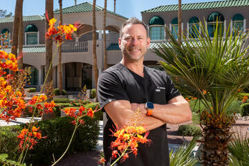 UNLV School of Dental Medicine Alumnus of the Year Dr. Benjamin Barborka poses outside behind bright orange flowers