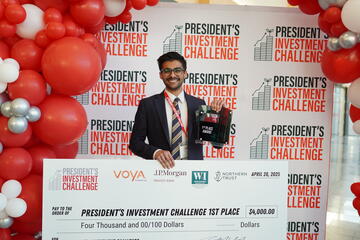 young male student holds large check from competition win