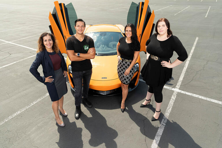 Four people around a Mclaren.