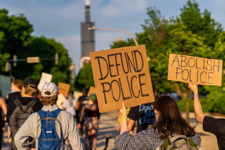 Protest signs read &quot;Defund Police&quot; and &quot;Abolish Police&quot;
