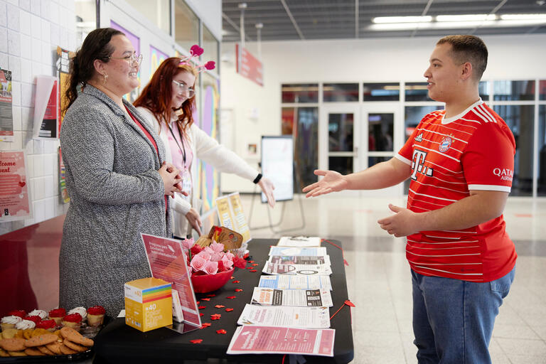 Student speaks with program representatives at a table.