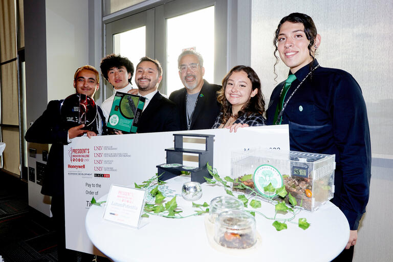group of students stands behind the model they used as part of a presentation