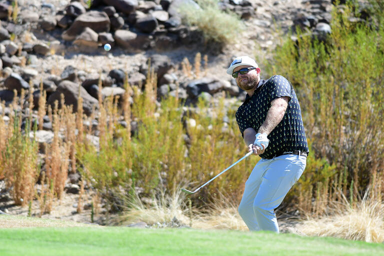 Erik Matthewson on the green swinging a golf club